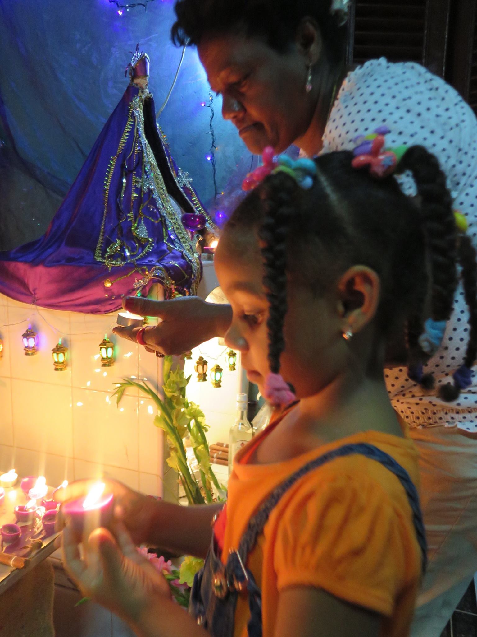 san lazaro, saint lazaro, celebration, worship, religion, santeria, catholicism, catholic, cuba, cuban, cuban streets, cuban celebration, streets of cuba, saint, patron saint of suffering, caribbean island, worshippers, girl, candle, light, lights, family